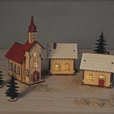 Casas e árvores em miniatura de madeira com luzes amarelas e detalhes vermelhos e brancos