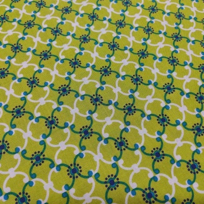 Tecido amarelo esverdeado com padrão geométrico branco, azul e vermelho