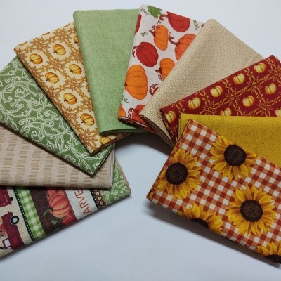 tecidos coloridos com padrões de girassóis, abóboras e carros dispostos em leque