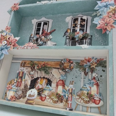 Miniatura decorativa em forma de casa azul com elementos natalícios