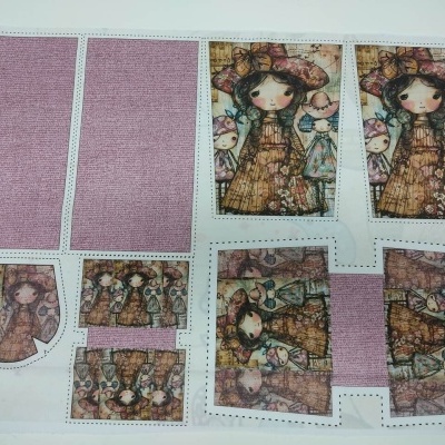 Folha de tecido estampado com imagens de bonecas em várias formas recortadas