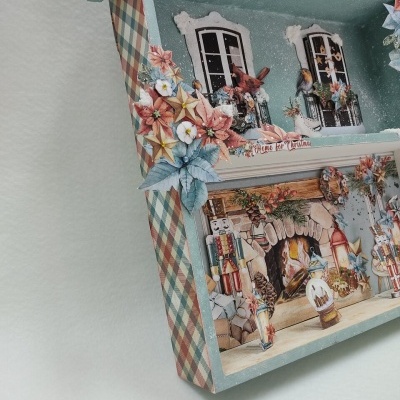 Casa decorativa de madeira azul com flores artificiais e decoração natalícia