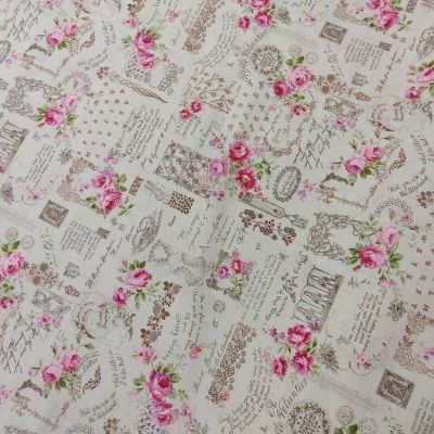 Tecido floral creme com rosas cor-de-rosa e texto em castanho claro
