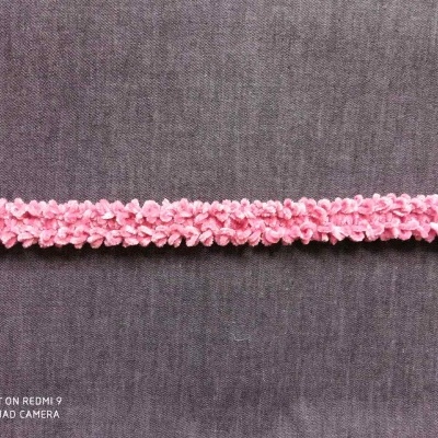 Faixa decorativa cor-de-rosa em tecido com textura frisada sobre fundo cinzento