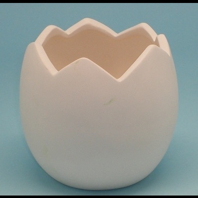 Vaso de cerâmica branca em formato de ovo partido sobre fundo azul claro.