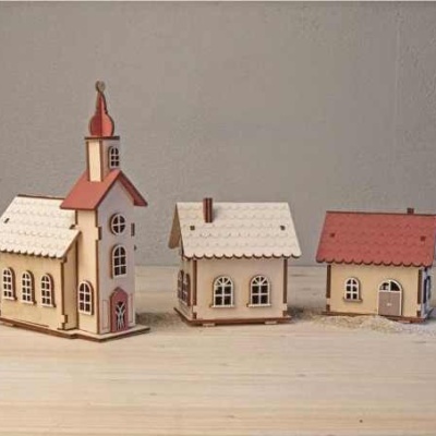 Três casas decorativas em madeira e duas árvores em fundo cinzento