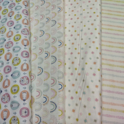 Cinco tecidos dobrados com padrões infantis de animais, arcos-íris, estrelas e listras coloridas