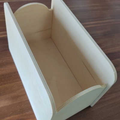 Recipiente de madeira clara retangular aberto com cantos arredondados sobre superfície de madeira escura