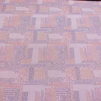 Tecido lilás claro com texto impresso em blocos rectangulares coloridos em tons pastel.