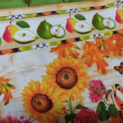 Tecido estampado com girassóis, folhas de outono, maçãs e borboletas.