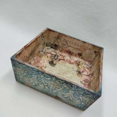 Caixa decorativa quadrada azul com padrão floral interior e texto visível