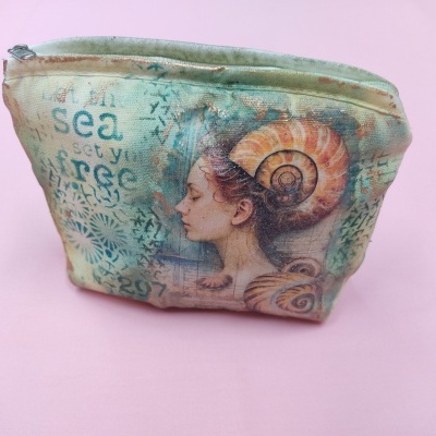 Nécessaire azul-esverdeado com imagem artística de mulher e conchas e texto em inglês