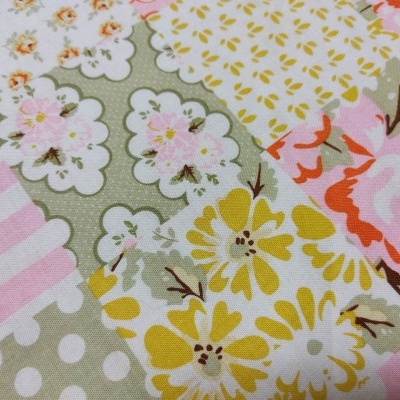 Tecido patchwork com padrões florais e às riscas em cores suaves.