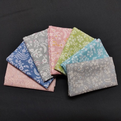 Conjunto de tecidos coloridos com padrão floral branco sobre fundo preto