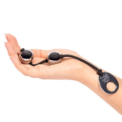 Bolas metálicas prateadas ligadas por cordão preto numa mão