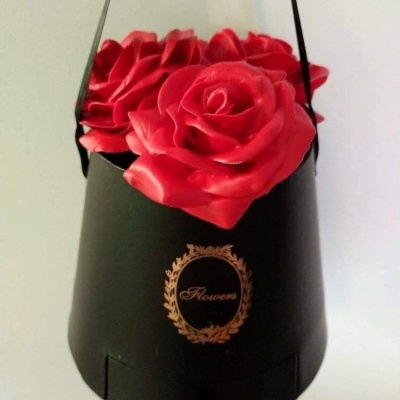 Arranjo de flores artificiais vermelhas em suporte preto com alça