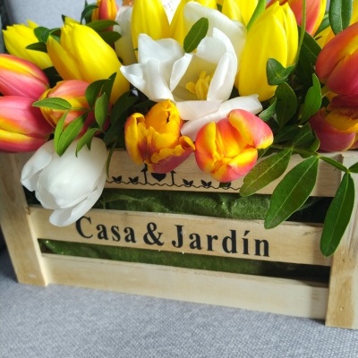 Arranjo floral com tulipas coloridas em caixa de madeira com texto Casa & Jardín