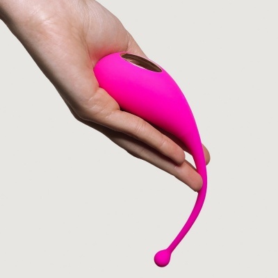 Dispositivo vibrador rosa em silicone segurado por uma mão