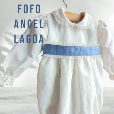 Macacão de bebé branco com gola e faixa azul pendurado num cabide