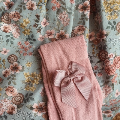 Meia-calça rosa com laço sobre tecido azul claro com flores