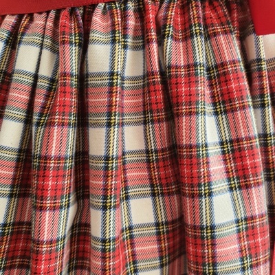 Tecido xadrez vermelho, branco, azul e amarelo com pregas e faixa vermelha