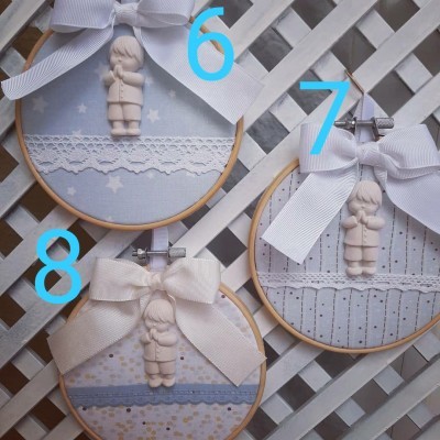 Três aros de bordar azuis com laços brancos e figuras infantis, numerados 6, 7 e 8, sobre fundo treliçado branco.