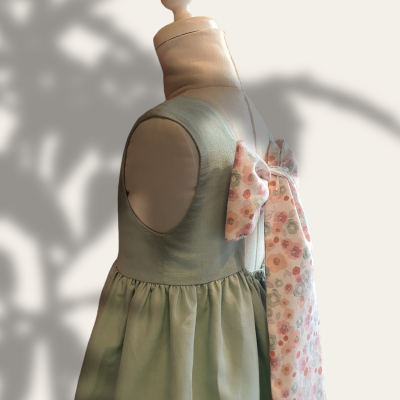 Vestido infantil verde claro com laço floral em manequim