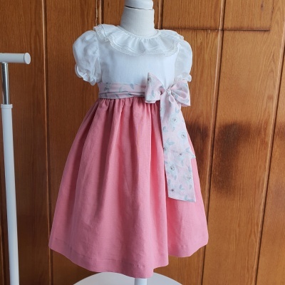 Vestido infantil branco e rosa com laço floral apresentado em manequim