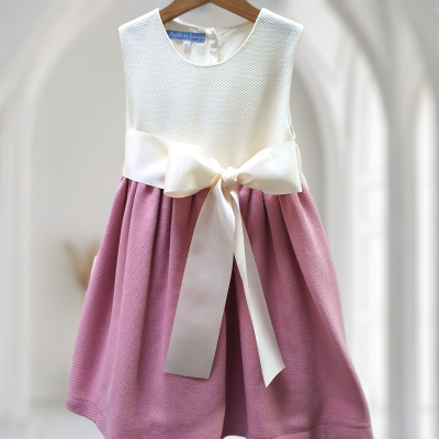 Vestido de criança branco e rosa com laço pendurado em cabide de madeira