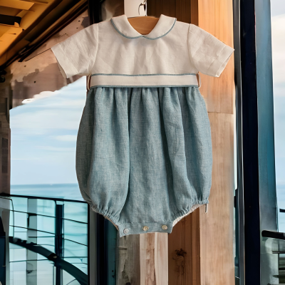 Roupa de bebé branca e azul claro pendurada com vista para mar