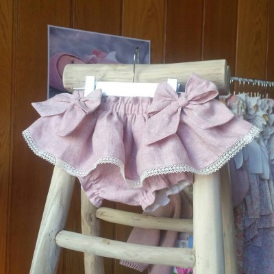 Calções de bebé cor de rosa com fitas de laço e renda pendurados