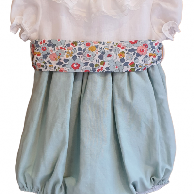 Jardineira de bebé branca e azul clara com faixa floral colorida e detalhe em folhos