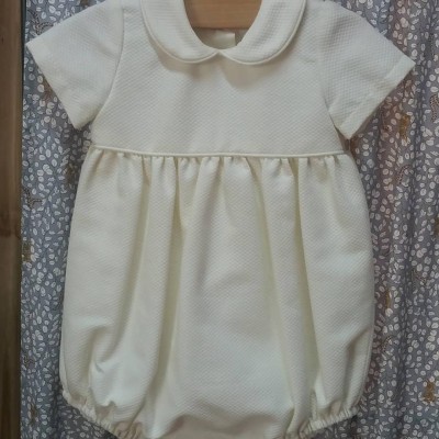 Babygrow branco matelassê com gola arredondada pendurado em cabide