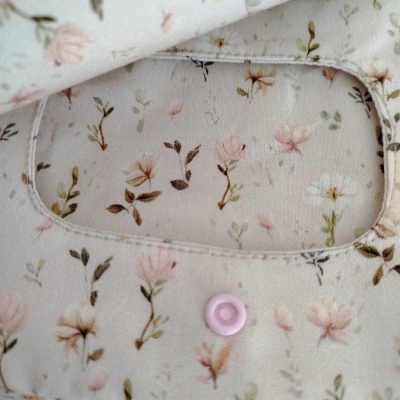 Tecido branco com padrão floral e botão rosa