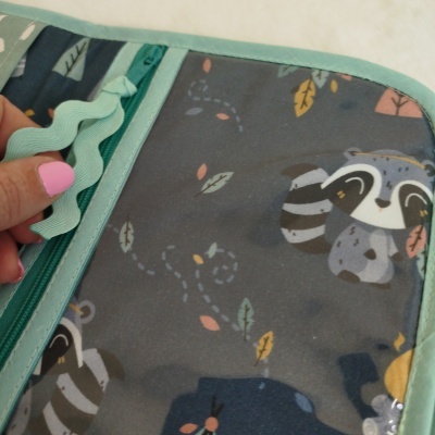 Organizador tecido com padrão de guaxinins e folhas, costura verde claro, mão a puxar fita dentada verde