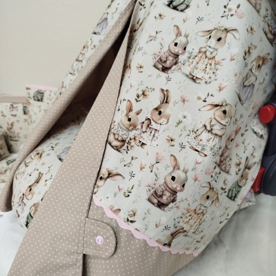 Capa de tecido com estampa de coelhos e flores em tons pastel e tecido bege com pontos brancos.