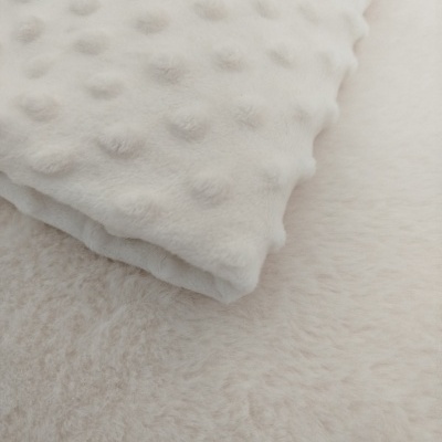 Manta ou almofada branca texturizada sobre superfície creme