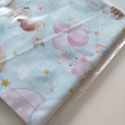 Tecido infantil azul claro com unicórnio e balões em embalagem plástica