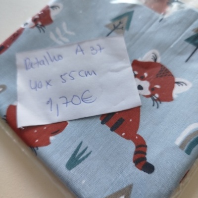 Retalho de tecido azul claro com raposas e padrão natural, com etiqueta manuscrita, dentro de embalagem plástica.