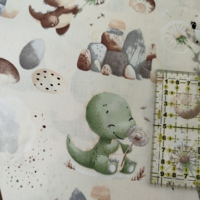 Tecido estampado com dinossauro verde e elementos naturais com régua transparente ao lado