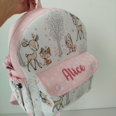 Mochila infantil branca e rosa com padrões de animais e nome Alice no bolso frontal