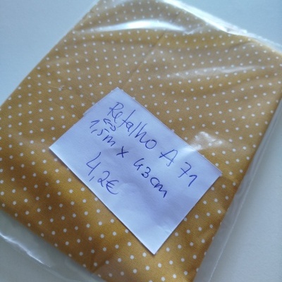 Retalho de tecido amarelo com bolinhas brancas em saco plástico