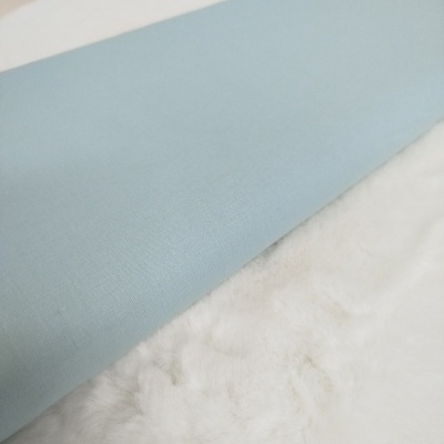 Almofada azul claro em tecido liso sobre superfície branca felpuda