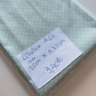 Tecido verde-água com pontos brancos e etiqueta manuscrita com indicação de preço e dimensões