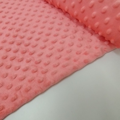 Tecido rosa com bolinhas em relevo parcialmente enrolado sobre fundo branco