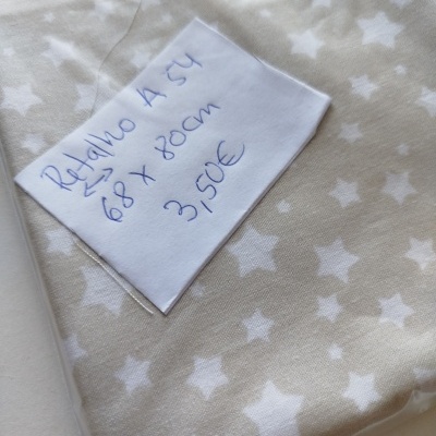 Tecido bege com estrelas brancas e etiqueta manuscrita com preço e medidas.