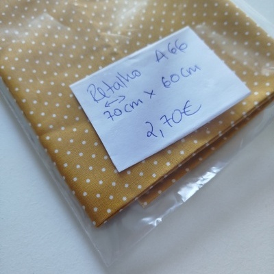 Tecido amarelo de bolinhas brancas embalado em saco plástico com etiqueta manuscrita