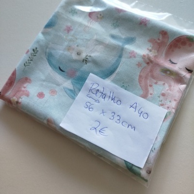 Retalho de tecido com padrão de animais marinhos em saco plástico com etiqueta manuscrita.