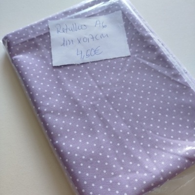 Tecido lilás com bolinhas brancas embalado com etiqueta manuscrita