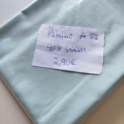 Pedaço de tecido azul claro com etiqueta manuscrita com medidas e preço